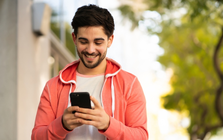 Young man smiling and looking at his mobile.