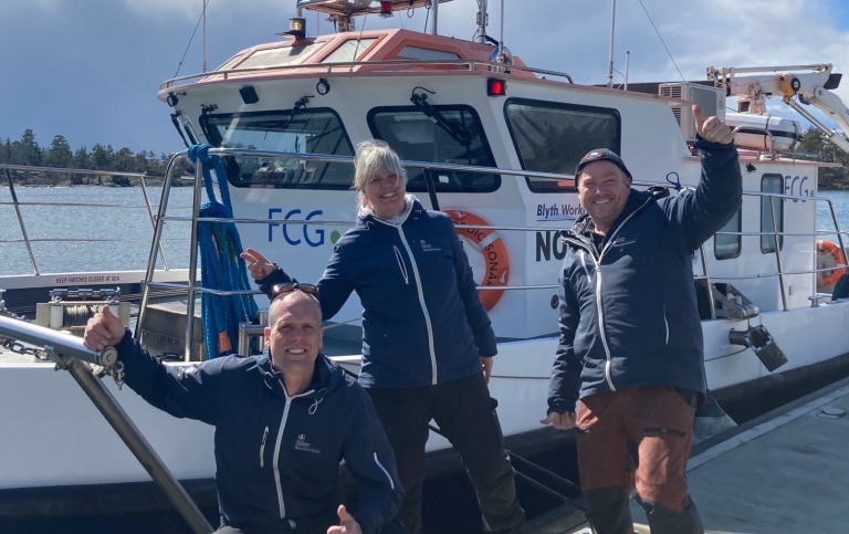 Happy staff members in front of our new research vessel