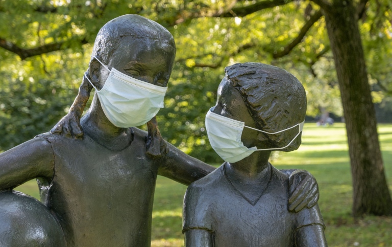 Staty av två lekande barn med munskydd