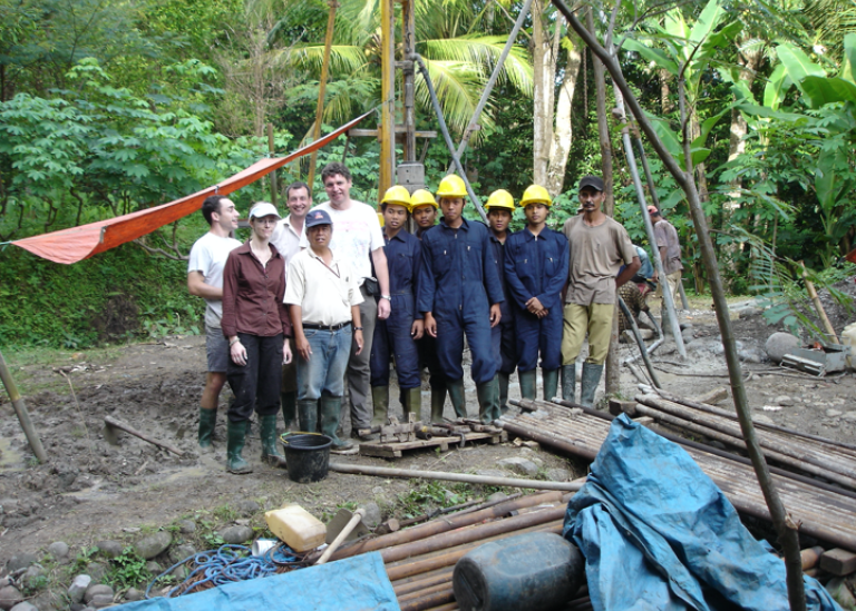 group of researchers standing behind a escavating site in the jungle with backets, tarpaulins, poles