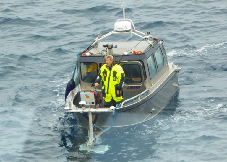 Researcher on survivor suit on board small research boat