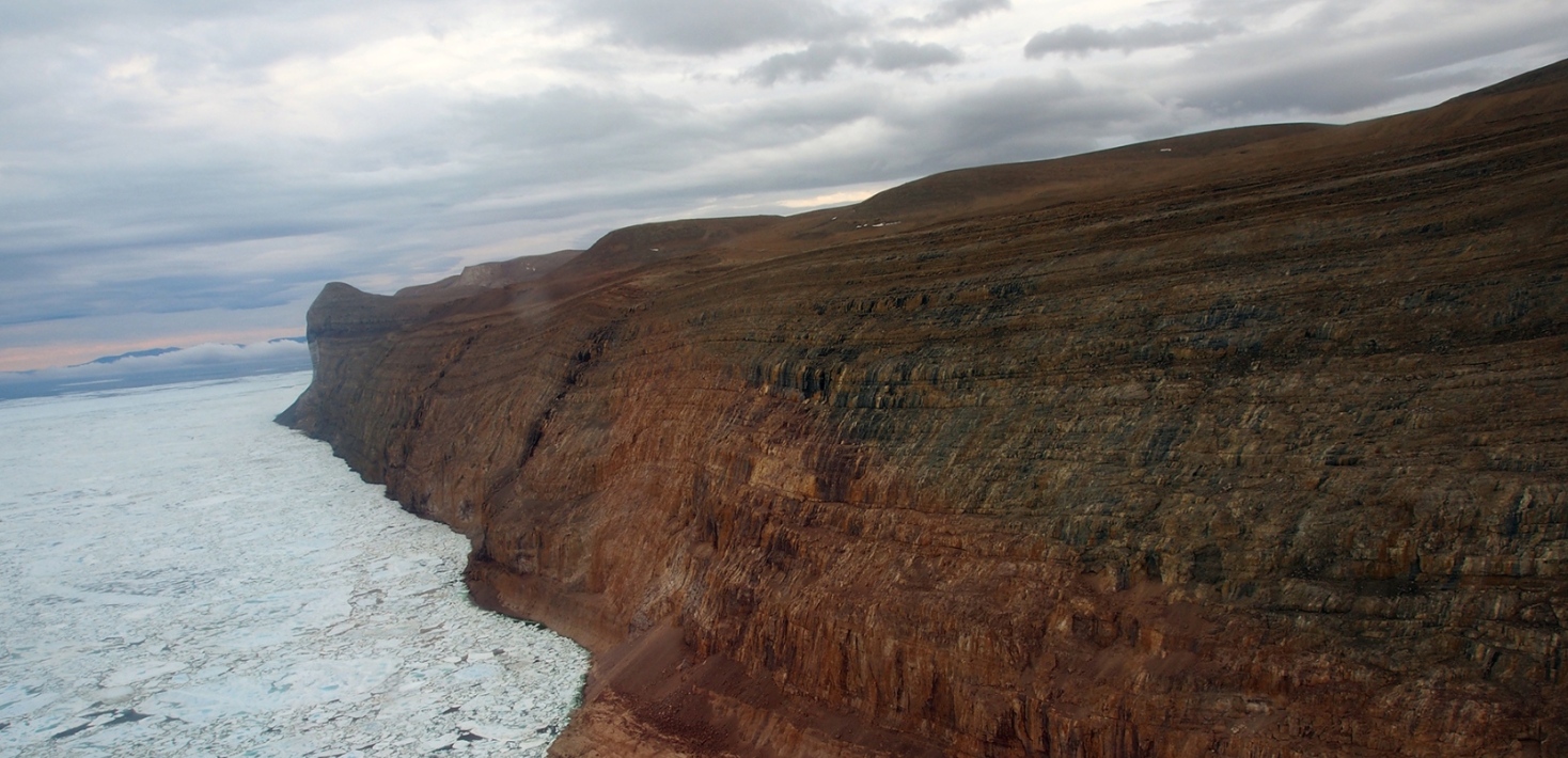 view of geological coast with icebergs and sea ice, dramatic clouds