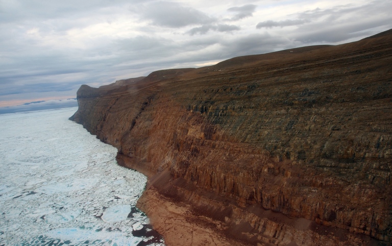 view of geological coast with icebergs and sea ice, dramatic clouds