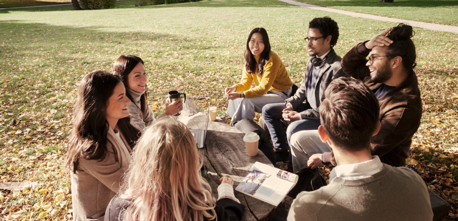 En grupp studenter utomhus på campus om hösten.
