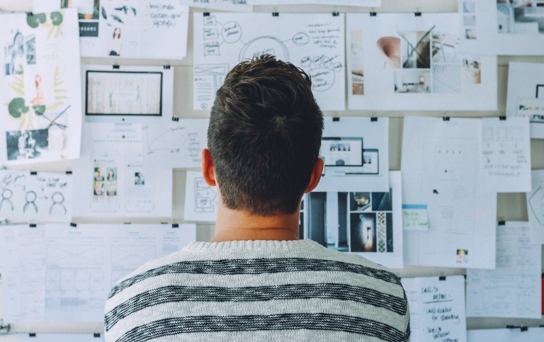 Man at board with many notes on it. Photo: Pexels from Pixabay.
