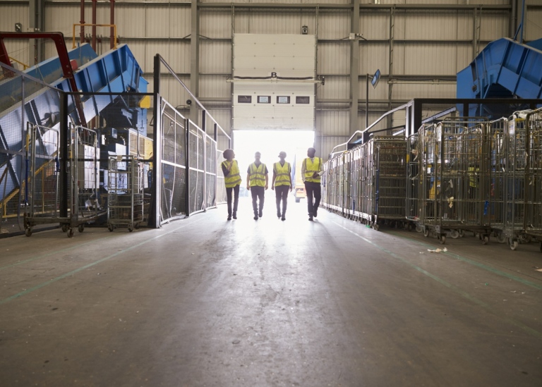 Four colleagues leaving a warehouse approach the exit