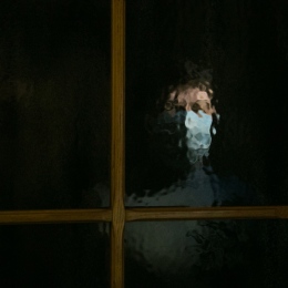 The face of a woman in a mask through dark glass. Home quarantine 