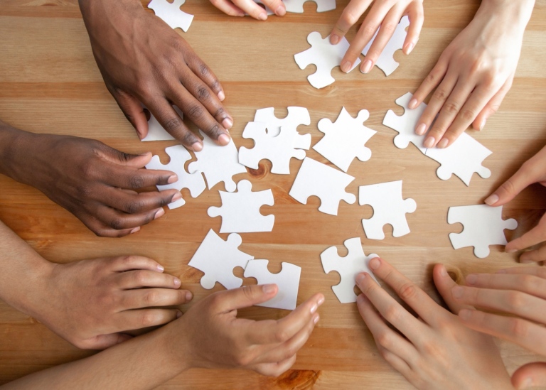 Diverse hands assembling a puzzle.