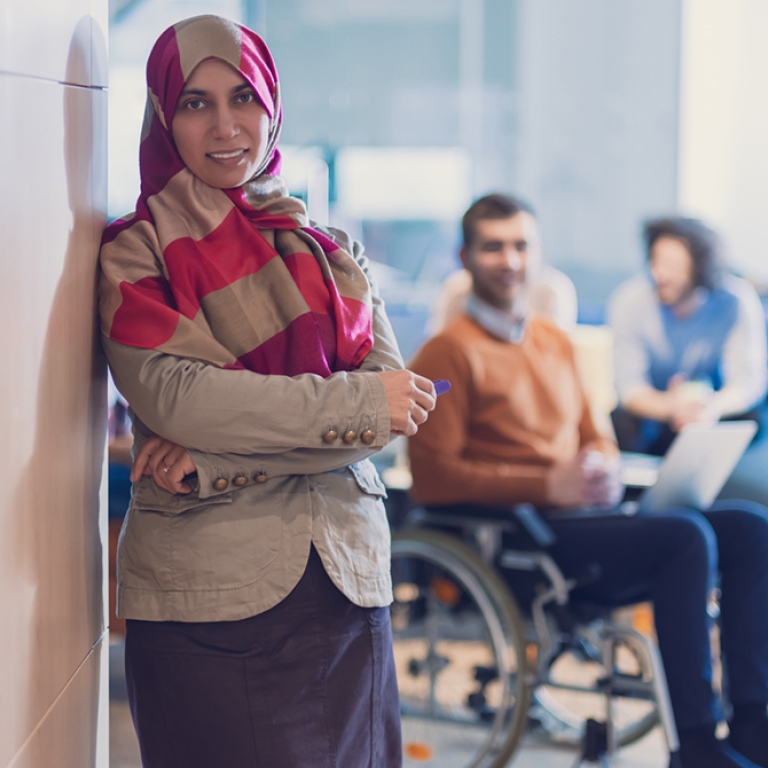 Woman wearing hijab, a man in wheelchair.