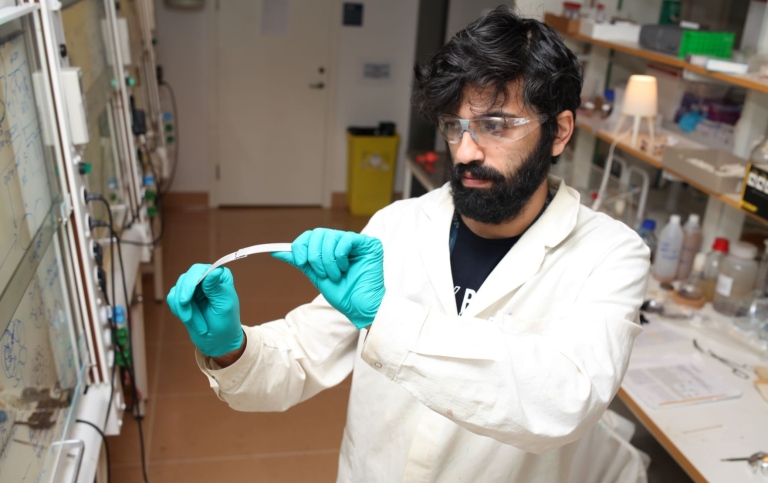M. Sc. Mohammad Morsali one of the researchers behind the study shows adhesive strength of the lignin based material by bending the bonded aluminum plates. Photo: MIka Sipponen