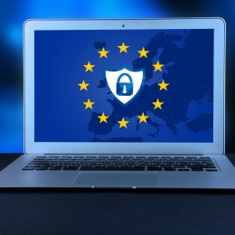 Lock icon and shield icon on the background of the EU flag, on the laptop screen