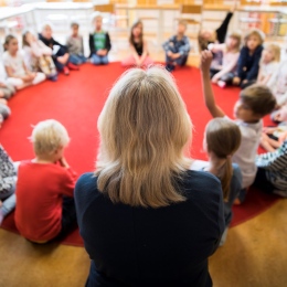 Förskoleklass är samlad i ring på en matta.