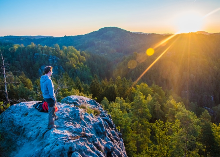 A person stands att a Viewpoint, looking out over a National Park in sunrise