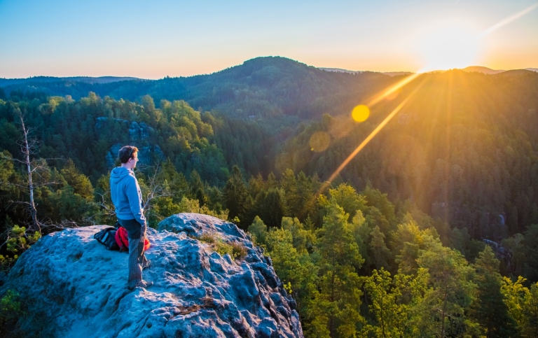 A person stands att a Viewpoint, looking out over a National Park in sunrise