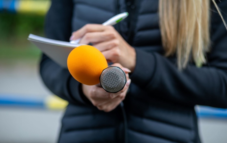 Närbild av journalist med mikrofoner och anteckningsblock. Foto från Mostphotos