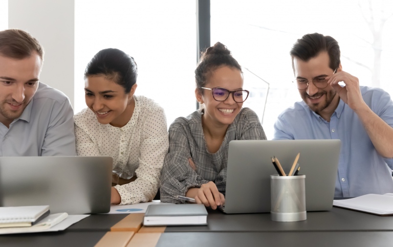 En grupp människorsitter vid ett bord med laptoppa på kontor. Foto: Aleksandr Davydov, MostPhotos