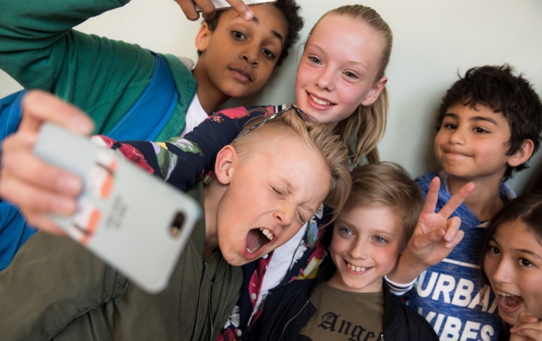 Flera barn som tar en selfie i skolkorridor