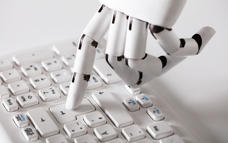 Robothand som trycker på "enter" på ett tangentbord. 