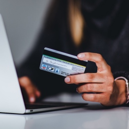 E-handel: en person sitter framför en dator med sitt bankkort i handen.
