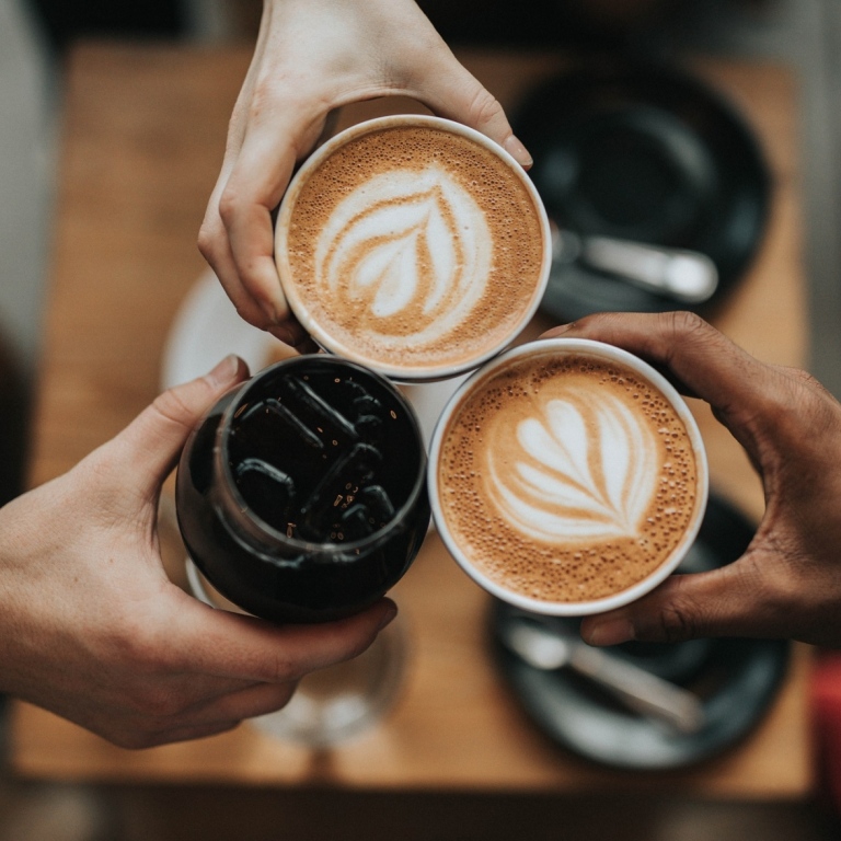 Tre händer som håller i kaffekoppar.