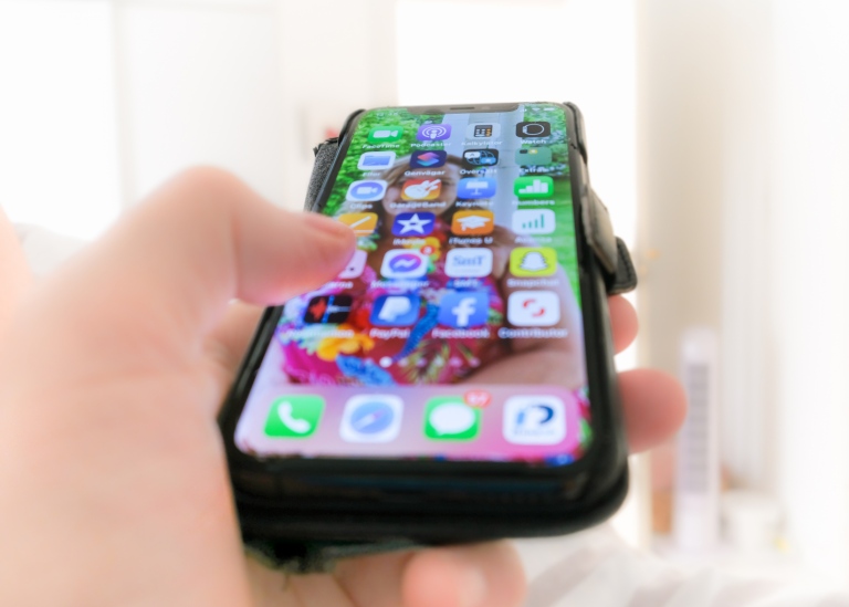 Närbild på hand som håller i en smartphone med måna applikationer på