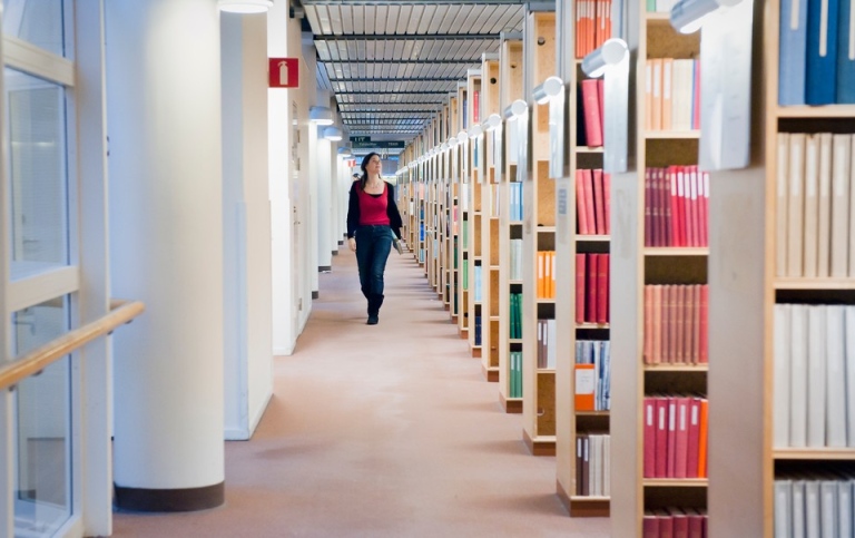 Woman walking alongside book shelves.