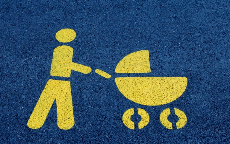 Ikon föreställande vuxen person med barnvagn.