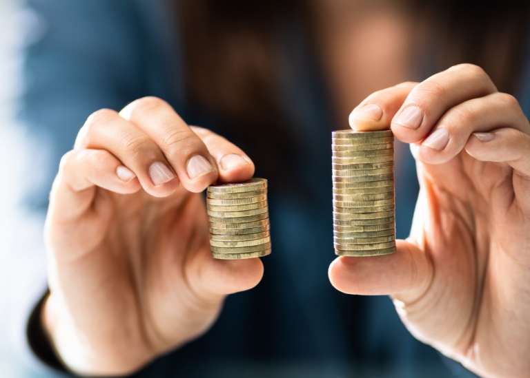 Person compares two piles of money, symbolizing wage gap