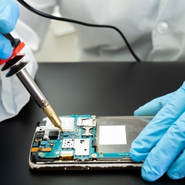 Genre photo: A technician working with tools inside a mobile phone.