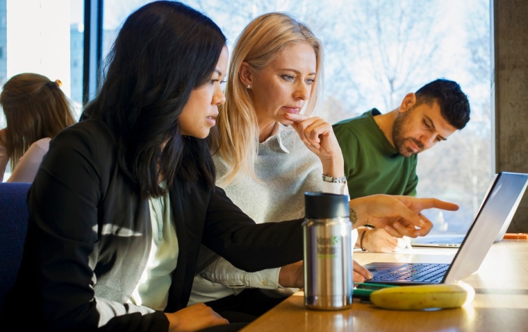 Två kvinnliga studenter sitter och diskuterar vid laptop. Foto: Jens Olof Lasthein.