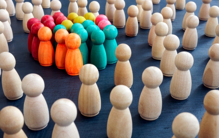 Social inclusion concept image - coloured figurines standing in group.