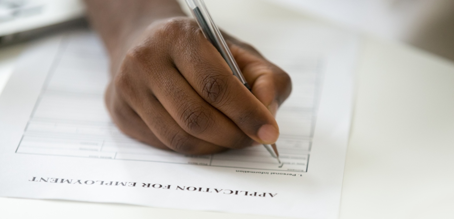 A dark-skinned hand filling in a job applicationa