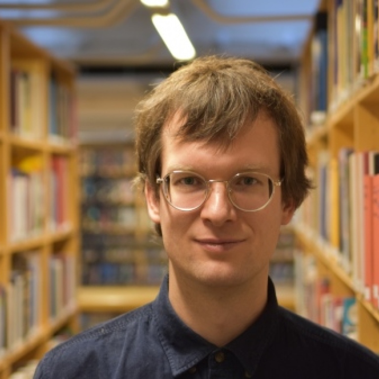 Närbild av Robert Östling med bokhyllor i bakgrunden. Foto: Stockholms universitet