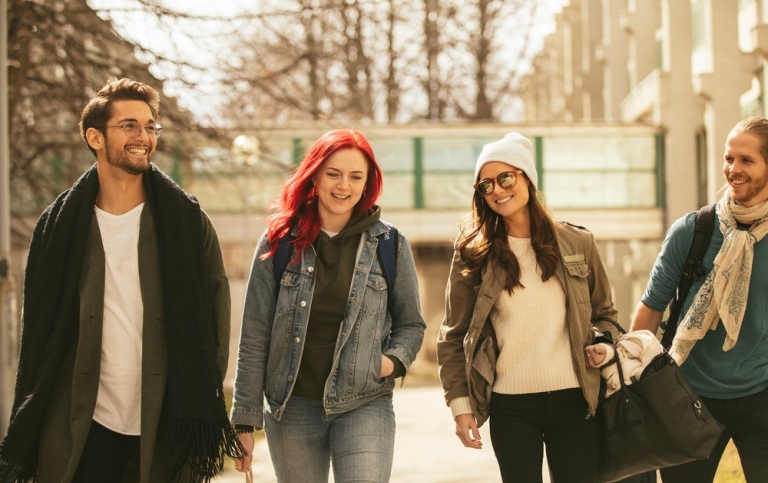 Fyra studenter promenerar på campus