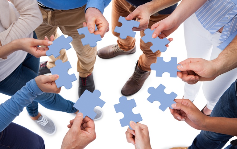 Genre photo: A group of people holding blue puzzle pieces. Photo: Andrey Popov/Mostphotos.