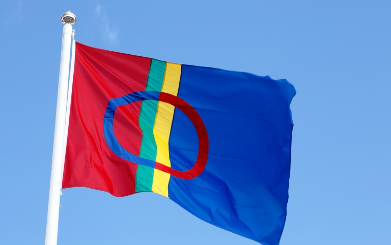 Samisk flagga som vajar mot en blå himmel.