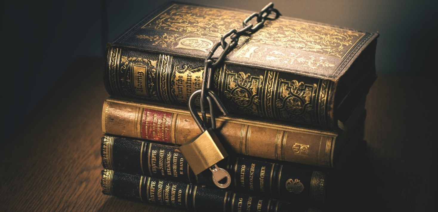 Illustrative image with a chain wrapped around ancient books, with an open lock