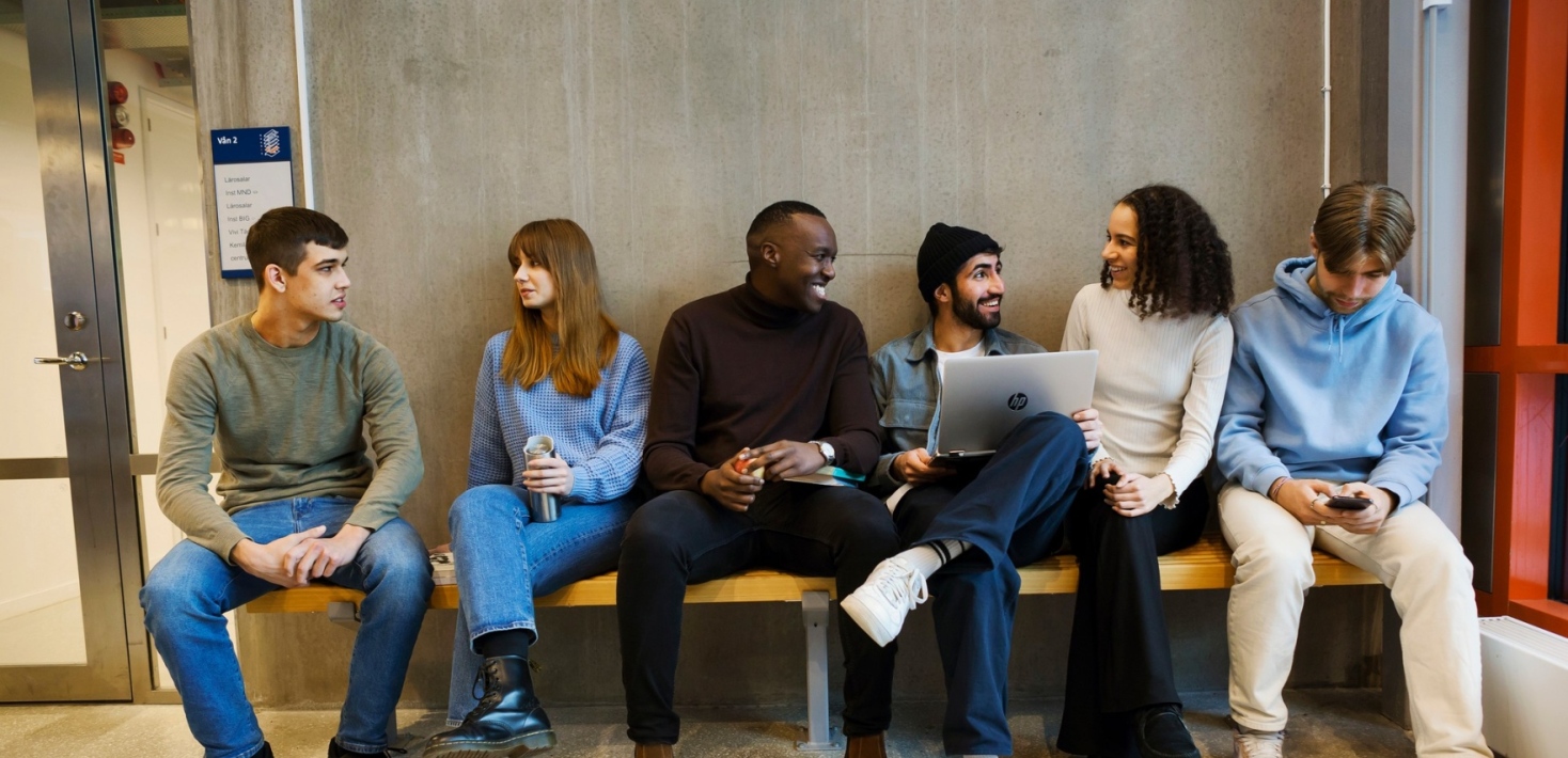 En grupp studenter sitter på en bänk.