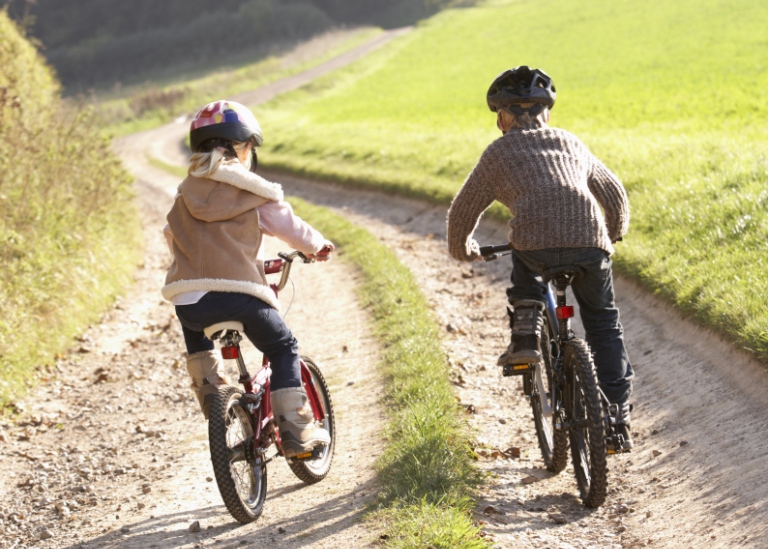 Tvpå barn cyklar på en grusväg