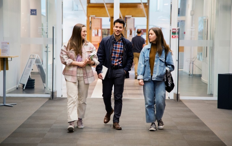 Three students walking in the library.