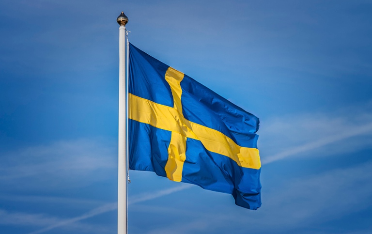 The Swedish blue and yellow flag against a blue sky. Photo: Marie Wennersten, MostPhotos