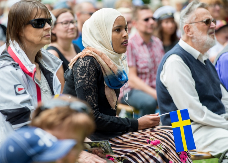 Nationaldagsfirande - ung tjej i slöja bredvid äldre personer med svenskt utseende