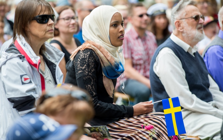 Nationaldagsfirande - ung tjej i slöja bredvid äldre personer med svenskt utseende