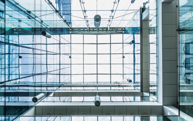 Genre photo: A building with several floors and glass ceiling, seen from the inside and looking up.