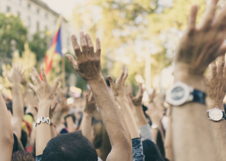 Genrebild: En folkmassa sträcker sina händer i luften, illustrerar forskning om e-demokrati