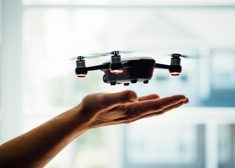 Genre photo: A person holding their hand under a drone flying. Illustrates research.