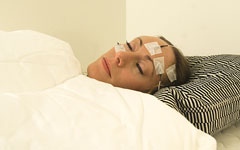 An image portraying a sleeping woman with measuring equipment on her head