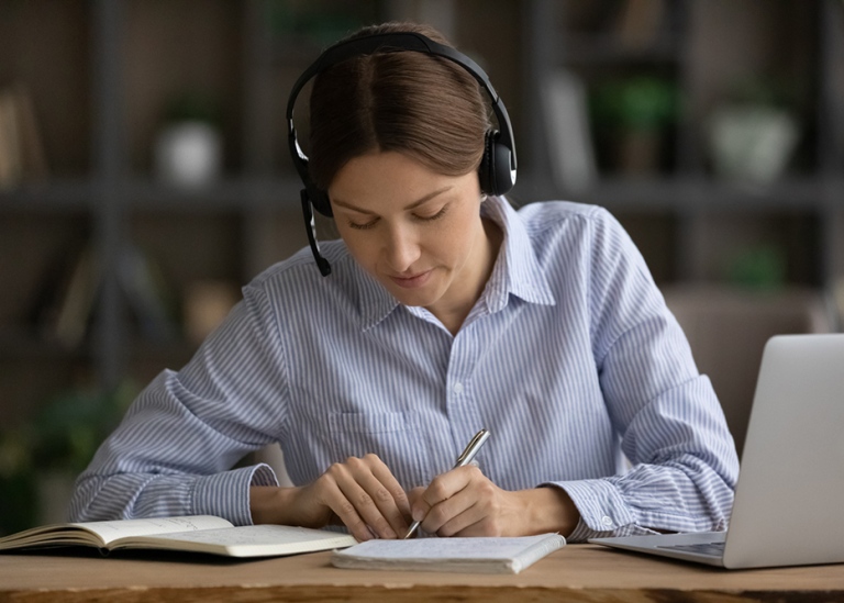 Woman laptop headset taking notes. Photo: Aleksandr Davydov MostPhotos