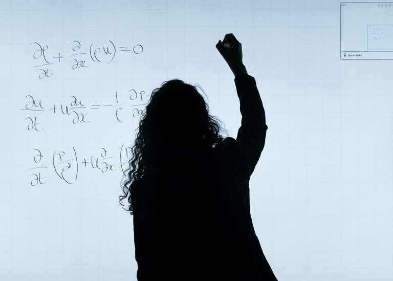 Silhouette writing partial derivatives on whiteboard.