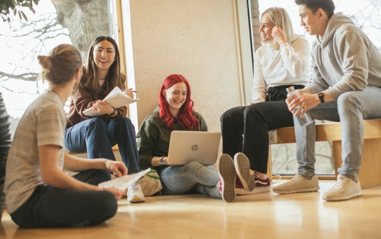Fem studenter sitter på golvet med dator och pratar. Foto: Niklas Björling